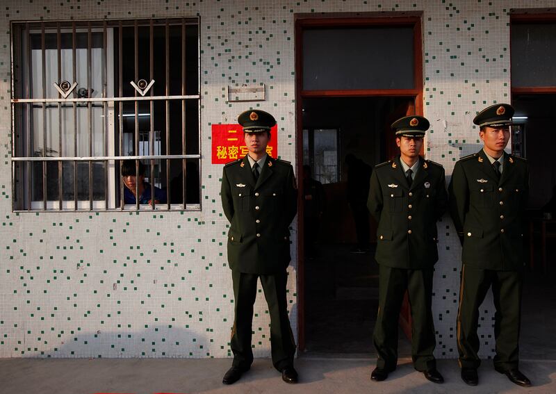 An election worker, left, looks out from a classroom guarded by police officers during vote counting at a school turned into a polling station in Wukan village in Lufeng, Guangdong province, Feb. 1, 2012.
