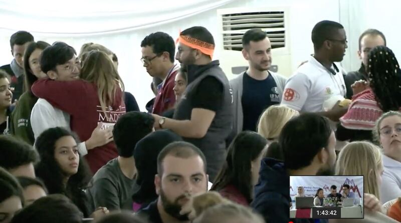 日前在卢安达召开的世界医学生联盟会长选举,台湾学生李柏锦(左立白衬衫者)获六成选票,取得压倒性胜利。(世界医学生联盟直播网站截图)