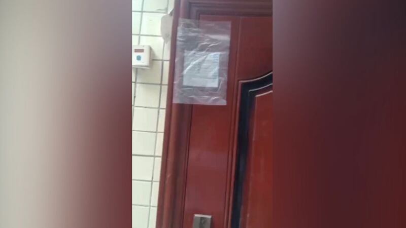 谢文飞的住所大门,贴着一个写有“物证封存”的塑料袋。(志愿者提供/记者乔龙)