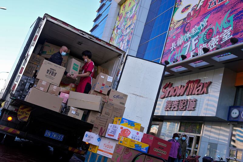 2022 年11月15日,北京一家购物中心外,工人在卡车上装载货物。(美联社)