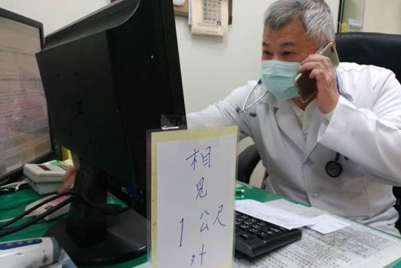 医师看诊时拿出自制保持距离手板。( 读者提供)