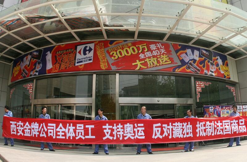 资料图片:2008年4月17日,当地公司的员工在陕西省西安家乐福超市外面举着“支持奥运会,反对西藏独立,抵制法国商品”的横幅。(路透社)