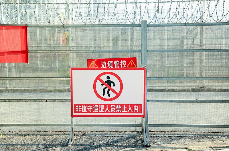 A part of a border wall between China and Myanmar with barbed wire and warning signs, in Ruili, west Yunnan province, Jan. 14, 2023. (Noel Celis/AFP)