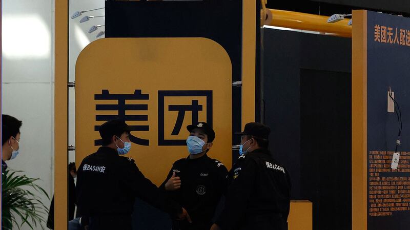 2021 年 4 月 30 日,在北京举行的互联网技术博览会上,保安人员在美团标志附近。 (美联社)