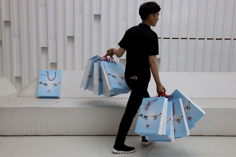 中美就贸易谈判陷于僵局,而苹果公司作为其中一家最具知名度的美国品牌企业,很有可能成为报复对象。图为2019年5月15日,北京华为展后,一公司人员双手拿着华为新产品包。(资料图/美联社)