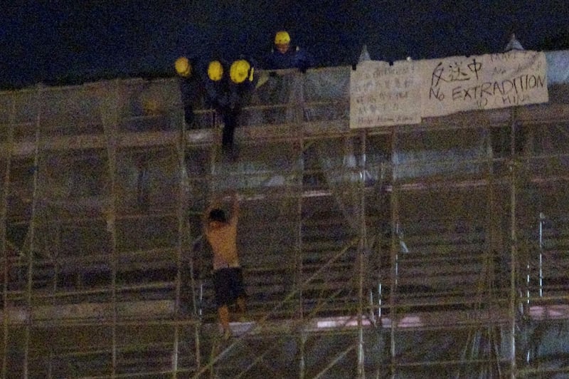 2019年6月15日,一名抗议者在太古广场平台悬挂标语时,从大楼周围的施工脚手架上掉下来,消防队员正试图营救他。(路透社)