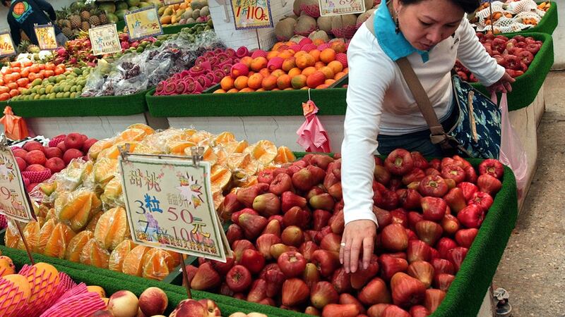 一名妇女在台北的当地水果市场挑选台湾热带水果。(美联社)
