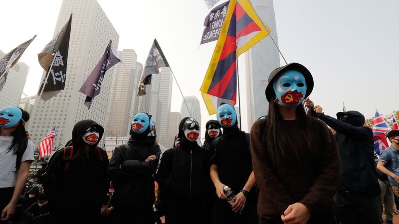 2019年12月22日,在香港中心地带举行主题为"声援维吾尔人权"的集会,身着黑衣的蒙面示威者高举写有"自由香港"字样的横幅。 (美联社)